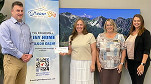 A woman holding a check next to three people