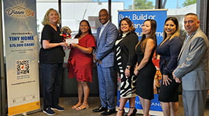 A woman being presented a check next to six people