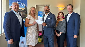 A woman holding a check with four other people nearby.