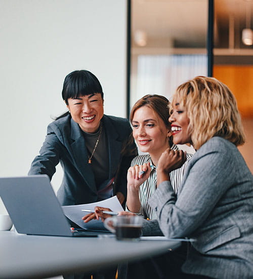 Three people looking at a laptop and smiling