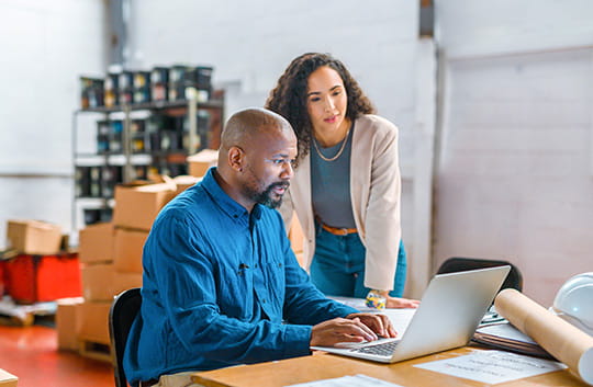 Two people in workspace looking at laptop