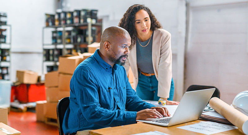 Two people looking at laptop in small warehouse