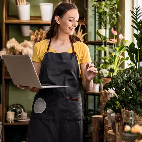 Businesswoman holds laptop while looking at shop display.