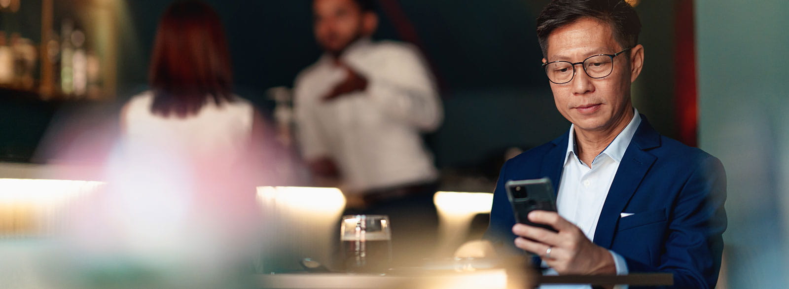 Businessman looks at mobile phone while sitting in restaurant