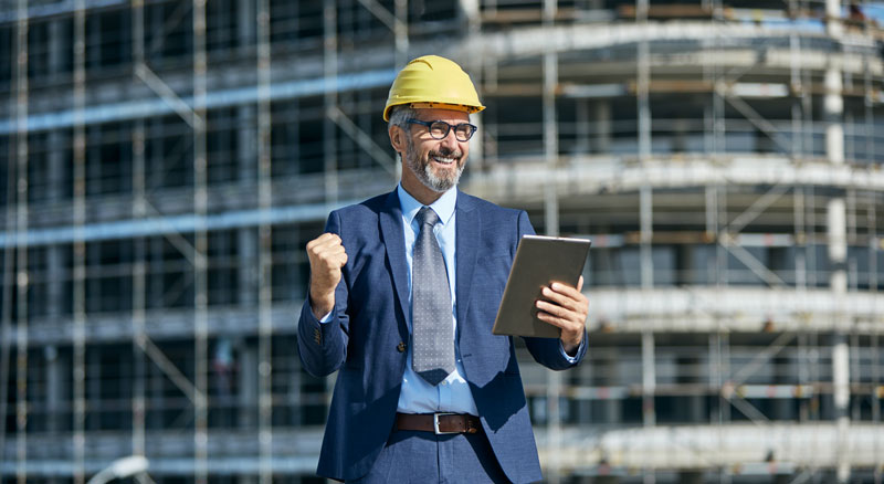 Smiling businessman in hard hat at construction site