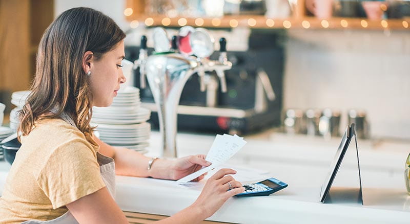 Person managing receipts at counter with calculator