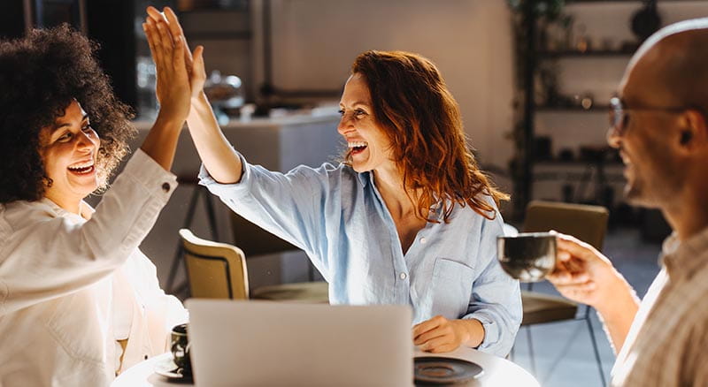 two people smiling and high-fiving in front of laptop