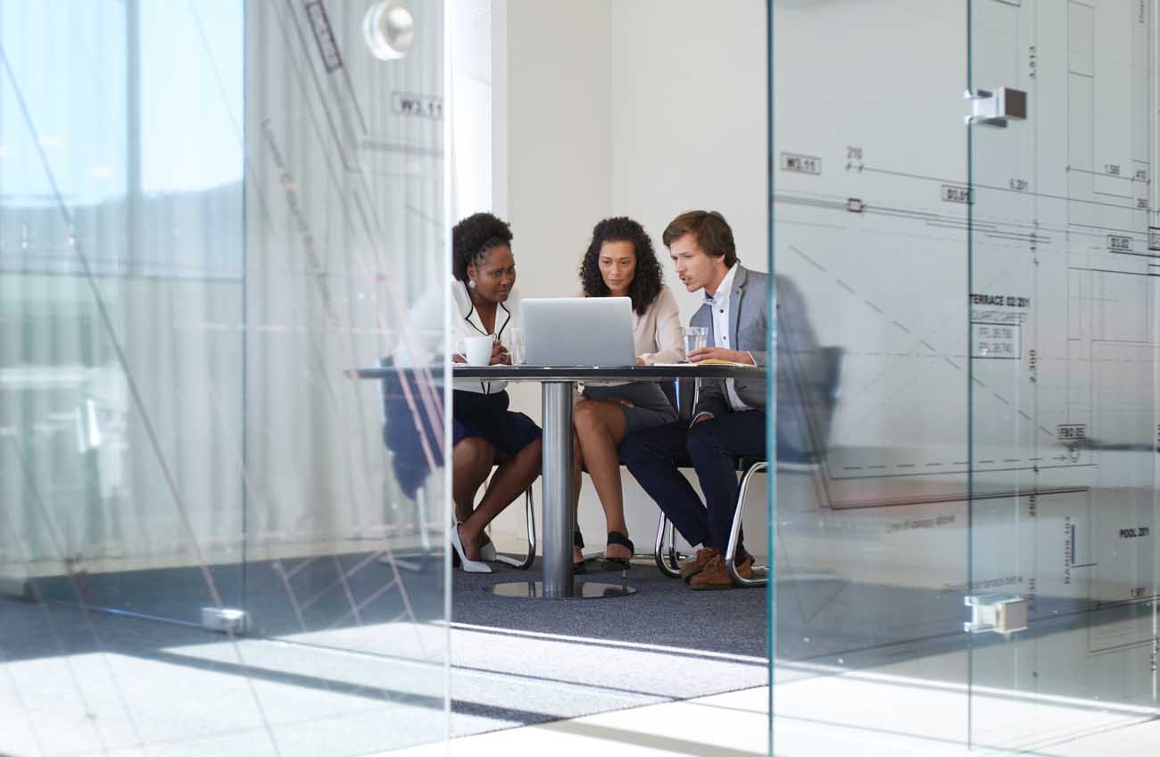Three people sitting at a table in a large office