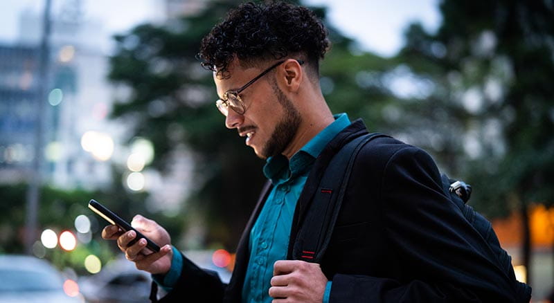 Person using cell phone while holding backpack