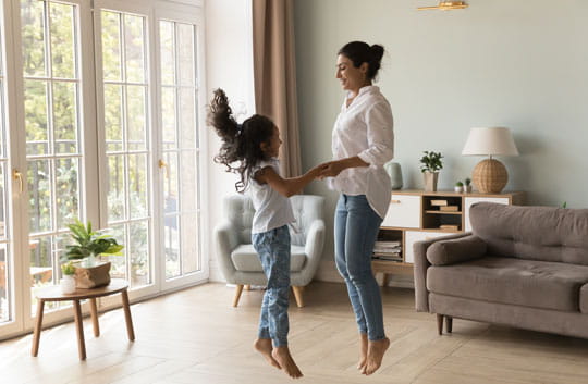 Excited mother and daughter jumping in living room