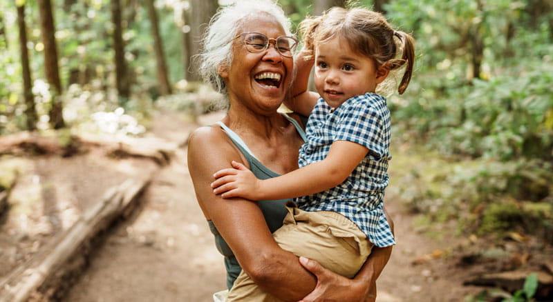 Laughing grandmother holds child while hiking