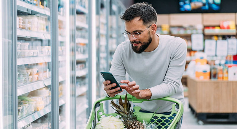 Person looking at phone while grocery shopping