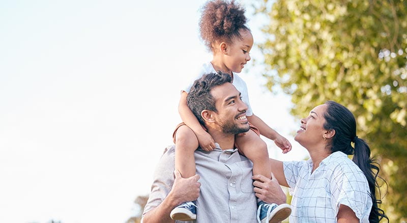 daughter on dad's shoulders smiling at mom
