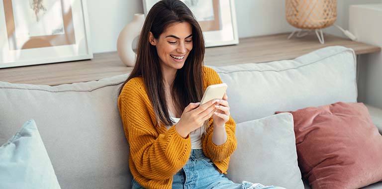 Woman sitting on a couch looking at a phone