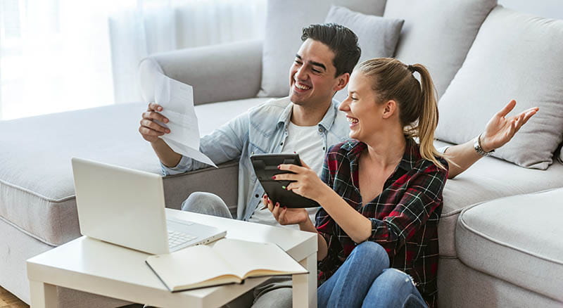 Couple talking while looking at calculator and a laptop