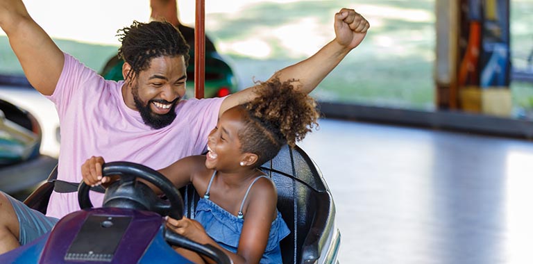 Father and daughter having fun driving a bumper car