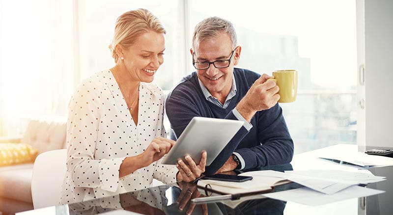 Two people looking at tablet with mug in hand