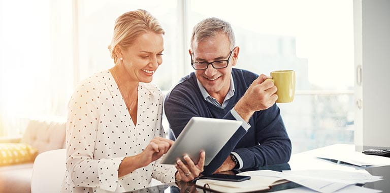 Two people looking at tablet with mug in hand