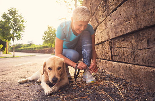Woman ties shoe while waking dog
