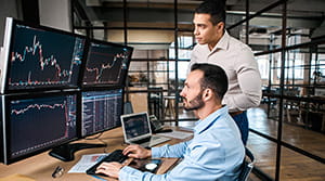 Two colleagues looking at multiple computer screens