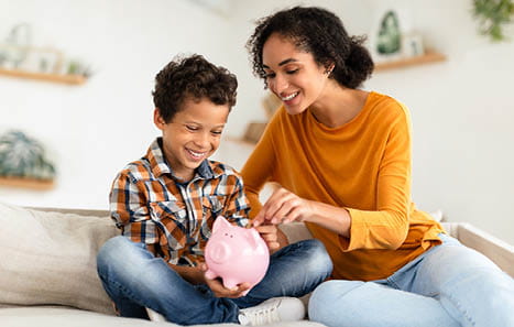 mother and son putting money in a piggy bank
