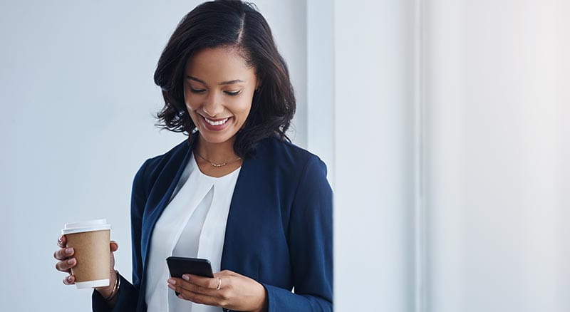 Person looking at phone with coffee in hand