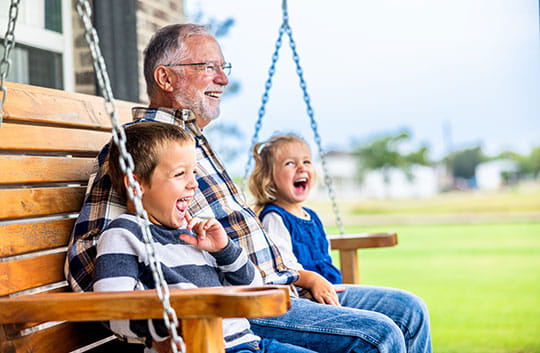 Grandfather sits on porch swing with grandkids