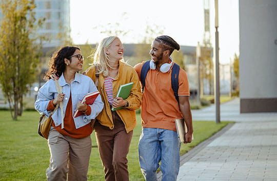 Three students walk on campus
