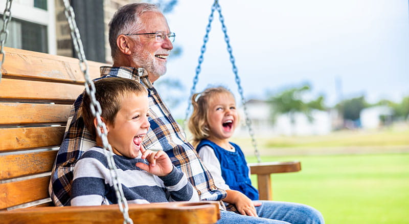 Grandfather sits on porch swing with grandkids