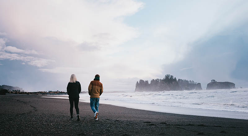 Two people walking on a cloudy beach on the Washington coast