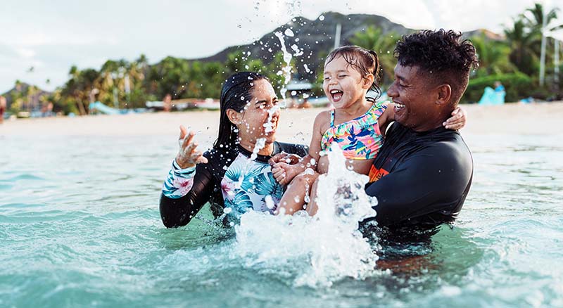 Parents splashing with daughter in pool