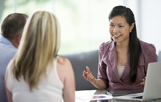 Asian Woman banker sitting at a desk with a middle-age couple