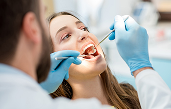 Banner Bank benefits illustrated by a dentist examining brunette woman's teeth with mirror