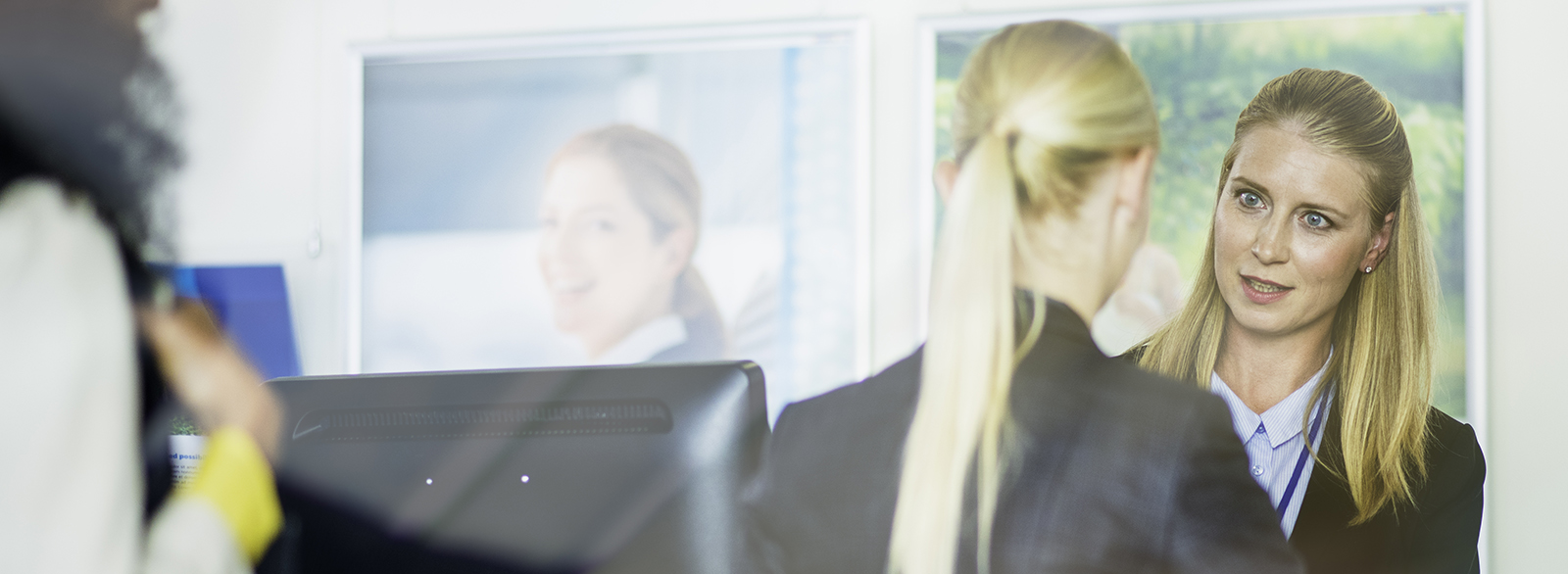 Blonde female banner bank teller assisting a client