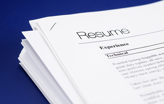 Stack of resumes piled up on a table with blue background
