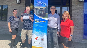 A man holding a check next to three other people.