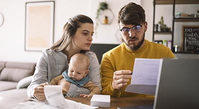 People looking at bills with baby on lap