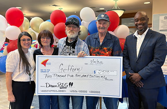 Dream Big monthly winner, Geffory with check and team