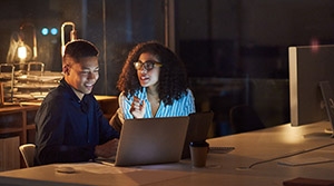 Small business owners working late with laptops