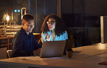 Small business owners working late with laptops