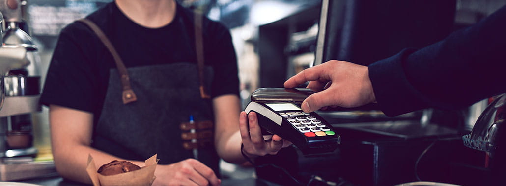 Person paying with phone at merchant card reader