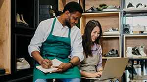 Two people in a shoe store looking at a laptop