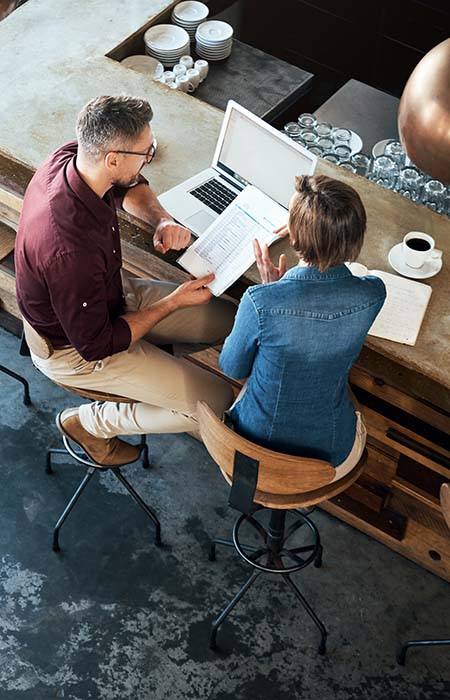 Two colleagues with papers and laptop in restaurant