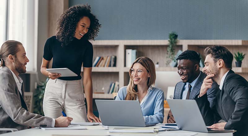 Colleagues smiling and looking at computers in an office space