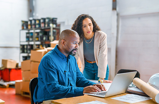 Two people in workspace looking at laptop