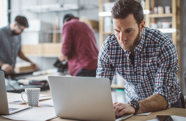 Person on laptop while two others work in background