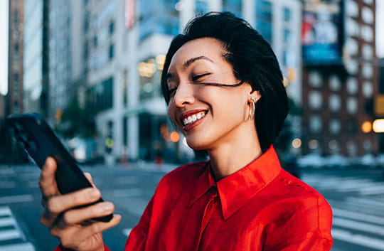 Person looking at phone and smiling in the city