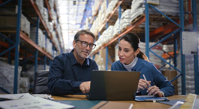 Two people looking at a laptop in a warehouse
