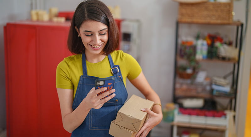Person smiling while holding phone and small boxes