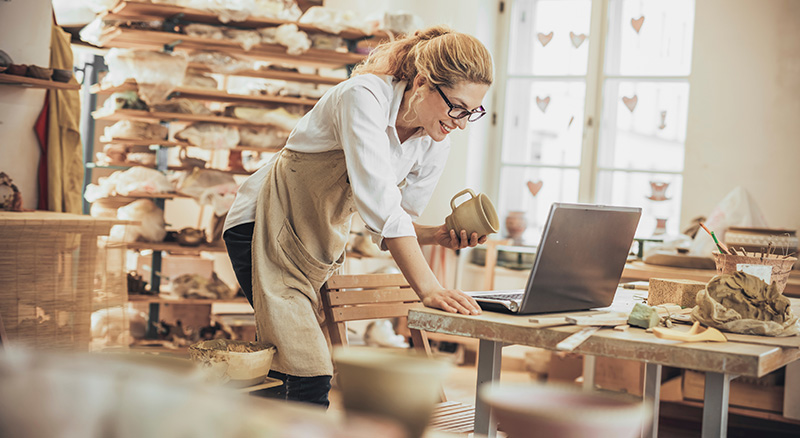 Pottery business owner looks at finances on her laptop using Banner Online Banking